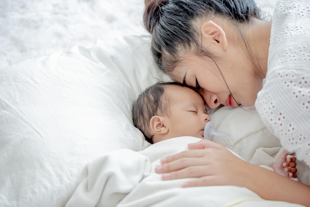 Il bambino e la madre asiatica dormono e toccano il suo bambino con tenerezza e tenerezza