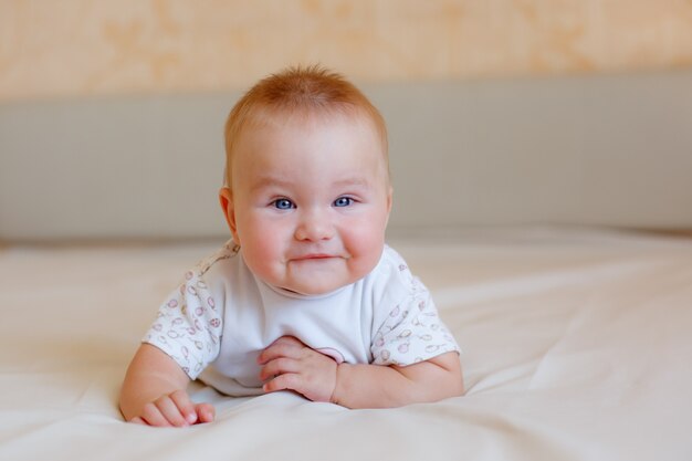 Il bambino è sdraiato sul letto in camera da letto sorridendo