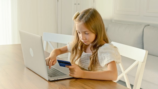 Il bambino esegue le operazioni con una carta di credito su un laptop