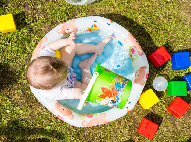 Il bambino fa il bagno in una piscina gonfiabile per bambini in una calda giornata estiva