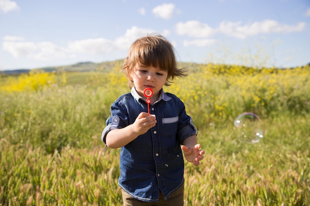 Il bambino fa le bolle di sapone all&#39;aperto