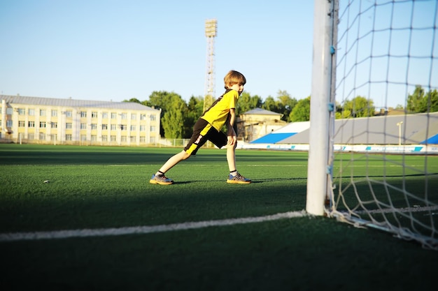 Il bambino fa sport allo stadio Il ragazzo si allena prima di giocare a calcio