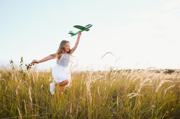 Il bambino felice con l'aereo giocattolo sta giocando al tramonto