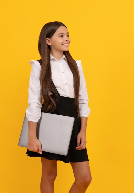 Il bambino felice in uniforme scolastica tiene l'istruzione informatica