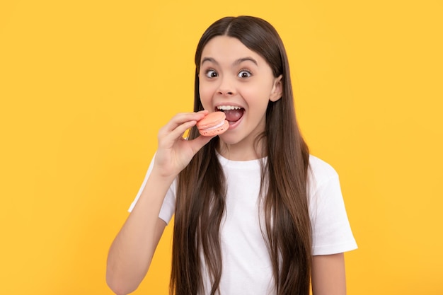 Il bambino felice mangia il bambino del forno del dessert tiene la confetteria francese del biscotto del macaron dell'amaretto