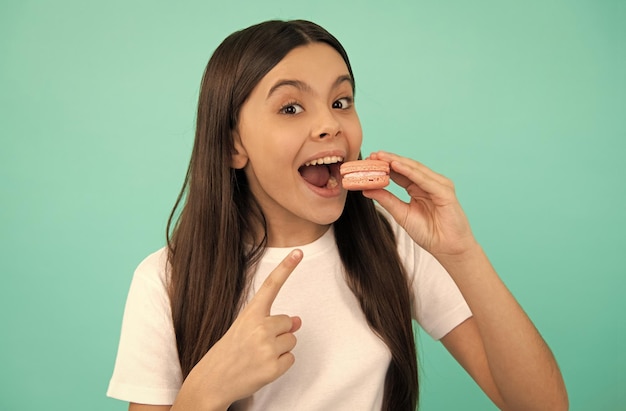 Il bambino felice mangia il macaron francese o l'amaretto dei biscotti dell'amaretto