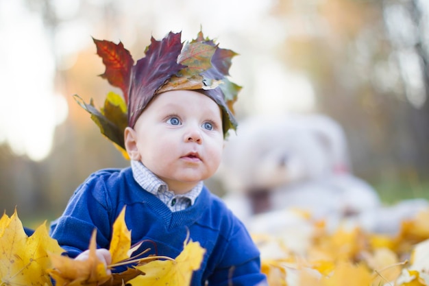 Il bambino felice nel parco autunnale gioca con le foglie