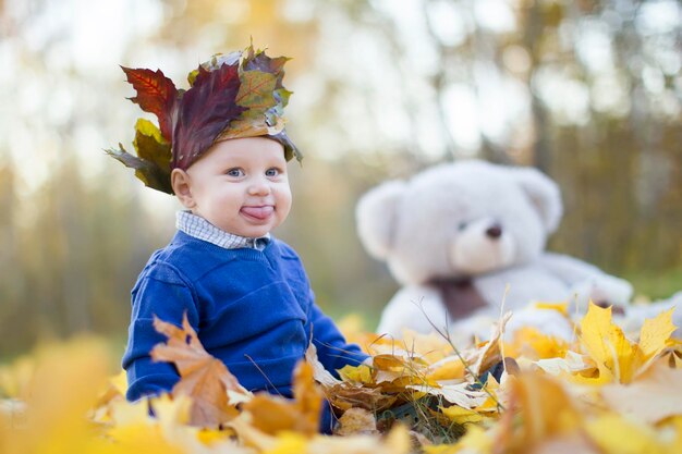 Il bambino felice nel parco autunnale gioca con le foglie