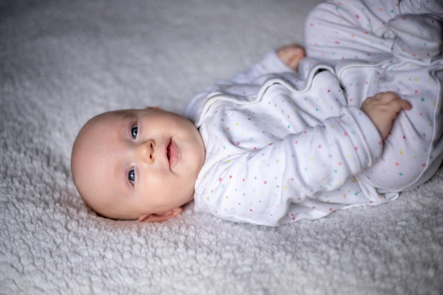 Il bambino felice si trova su una coperta bianca