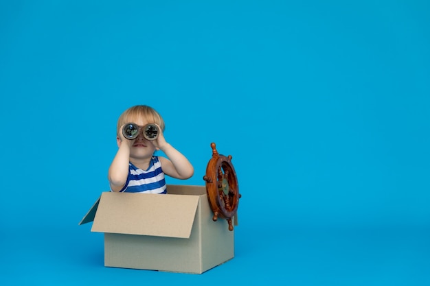 Il bambino felice sogna di diventare un capitano contro il muro blu.