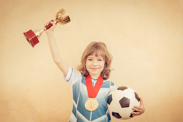 Il bambino finge di essere un calciatore. Concetto di successo e vincitore