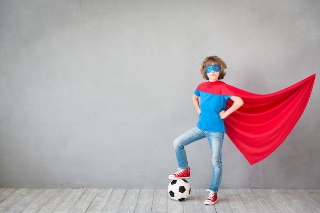 Il bambino finge di essere un supereroe del calcio Bambino che gioca con la palla a casa Il successo vince e l'immaginazione