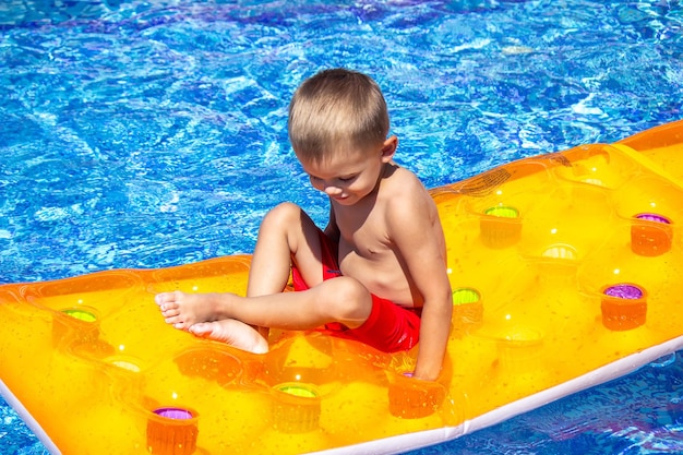 Il bambino galleggia su un materasso gonfiabile nel fuoco selettivo della piscina