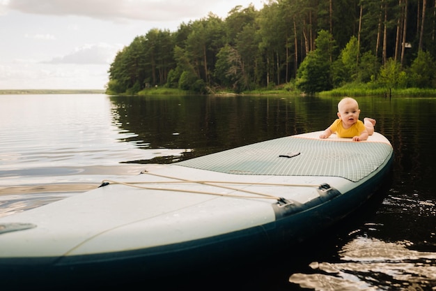 Il bambino giace galleggiante sull'acqua su una grande tavola da sup Sport acquatici