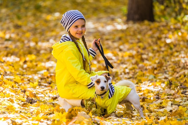 Il bambino gioca con Jack Russell Terrier nella foresta autunnale