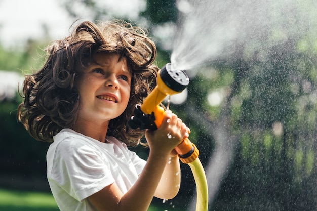 Il bambino gioca con l'acqua nel cortile in giardino