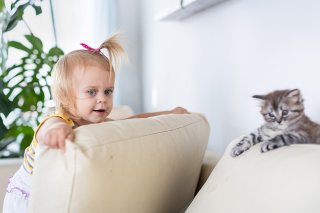 Il bambino gioca con un gattino sul divano