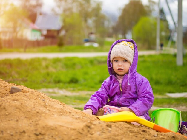 Il bambino gioca nella sabbia con una pala e un secchio