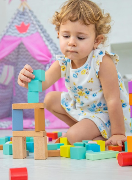 Il bambino gioca nella stanza dei bambini con un costruttore di legno Fuoco selettivo