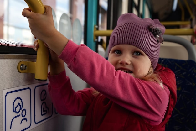 Il bambino guida l'autobus del trasporto pubblico moderno guarda fuori dalla finestra Bambina nel trasporto metropolitano