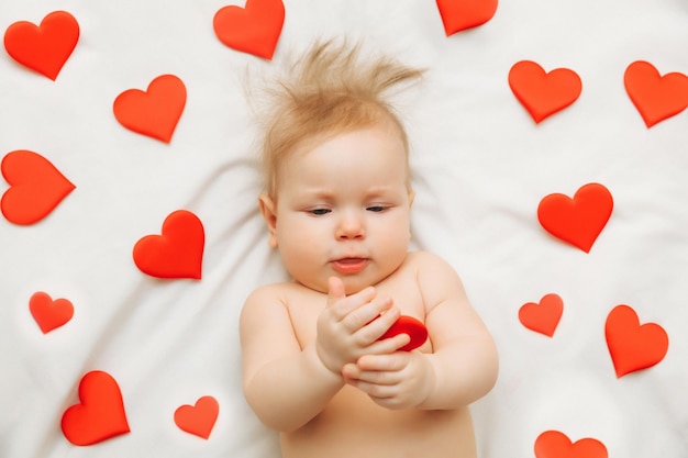 Il bambino ha 6 mesi sdraiato sul letto tra i cuori il concetto di amore e San Valentino
