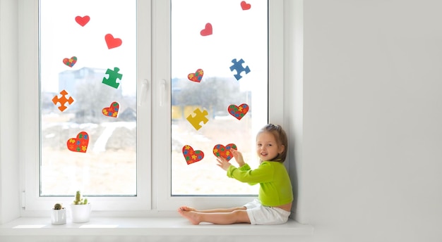 Il bambino ha decorato la finestra con cuori e puzzle in segno di sostegno per i bambini con autismo