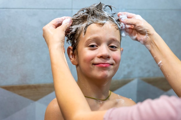 Il bambino in età prescolare si lava la testa in bagno con lo shampoo