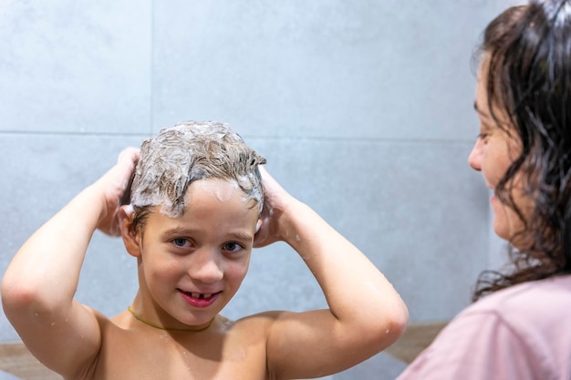 Il bambino in età prescolare si lava la testa in bagno con lo shampoo