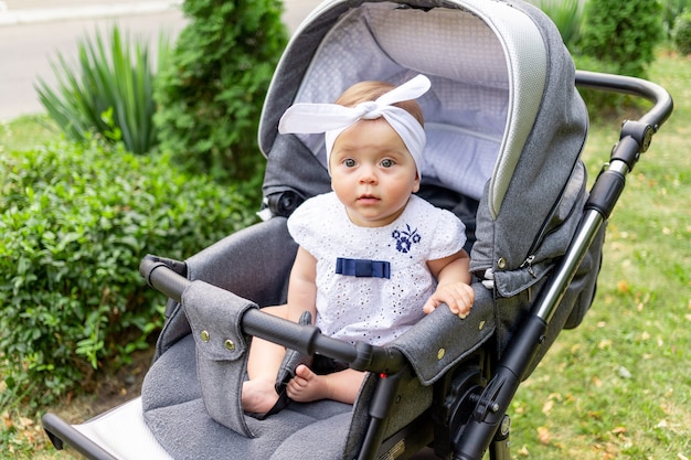 Il bambino in un passeggino cammina in estate in abiti bianchi