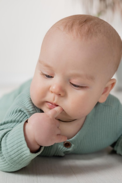 il bambino in una tuta di cotone verde impara a gattonare sul pavimento spazio di sviluppo del bambino per il testo