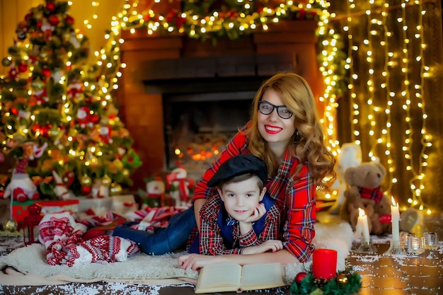 Il bambino insieme a sua madre a casa sullo sfondo delle decorazioni di Capodanno.