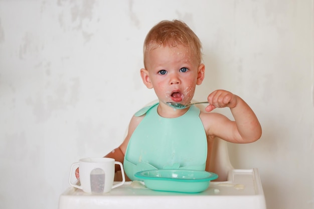 il bambino mangia con un cucchiaio e impara da solo