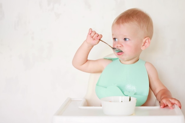 il bambino mangia con un cucchiaio e impara da solo