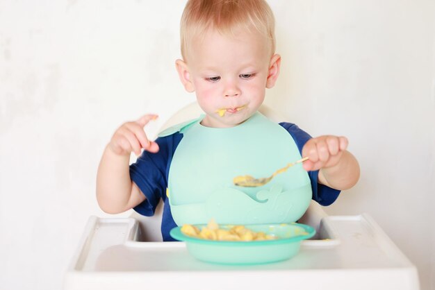 il bambino mangia con un cucchiaio e impara da solo