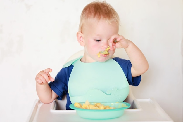 il bambino mangia con un cucchiaio e impara da solo