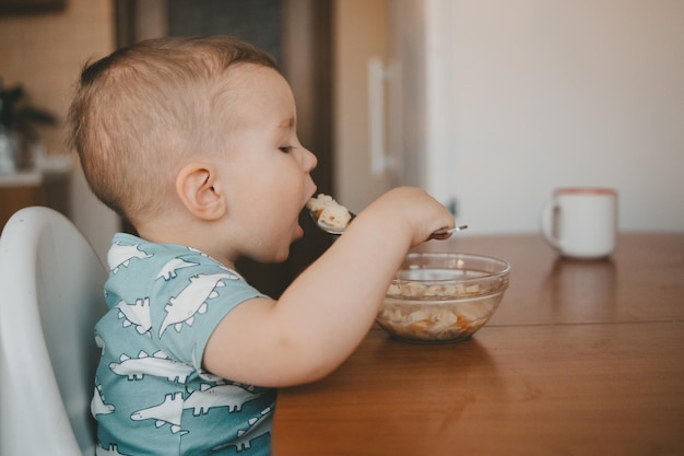 il bambino mangia da una lastra di vetro al tavolo della cucina