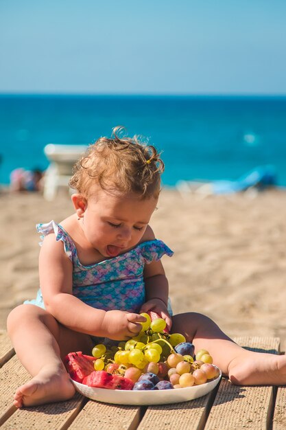 Il bambino mangia frutta in riva al mare. Messa a fuoco selettiva. Ragazzo.