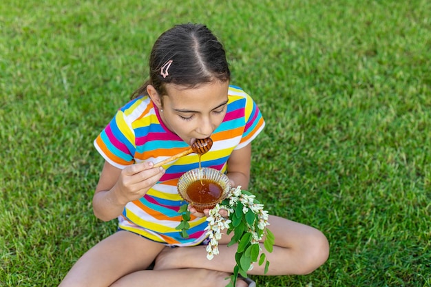 Il bambino mangia il miele in giardino Messa a fuoco selettiva