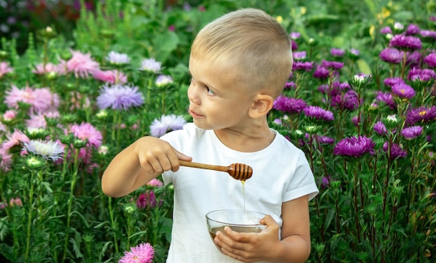 Il bambino mangia il miele in giardino.