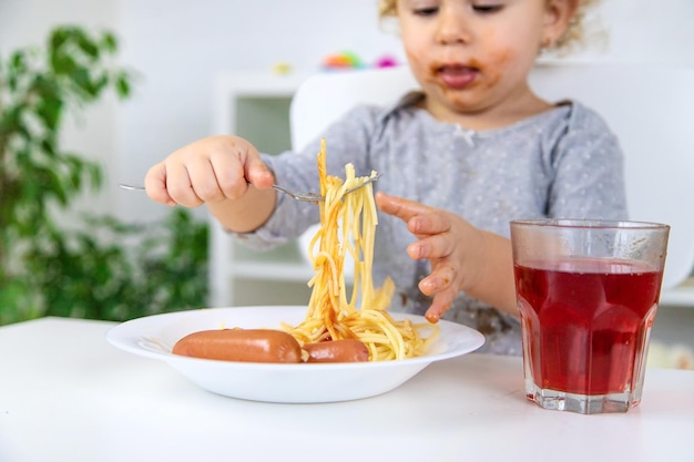 Il bambino mangia il pranzo degli spaghetti Fuoco selettivo