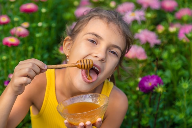 Il bambino mangia miele di fiori. Messa a fuoco selettiva. Natura.