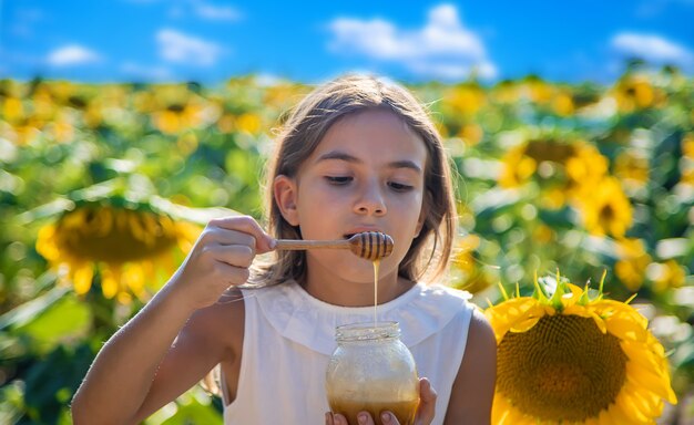 Il bambino mangia miele di fiori. Messa a fuoco selettiva. Natura.