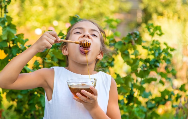 Il bambino mangia miele di fiori. Messa a fuoco selettiva.