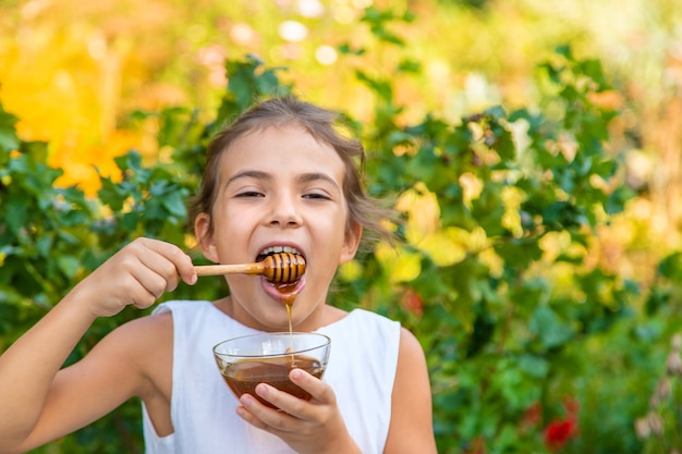 Il bambino mangia miele di fiori. Messa a fuoco selettiva.