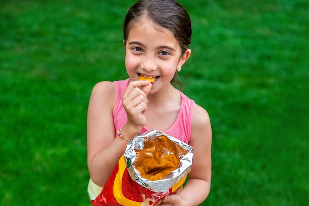 Il bambino mangia patatine nel parco Messa a fuoco selettiva