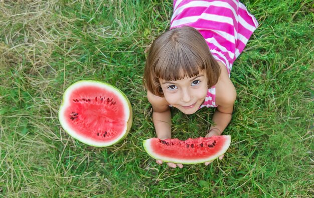 Il bambino mangia un'anguria nel giardino