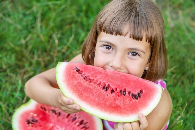 Il bambino mangia un'anguria nel giardino