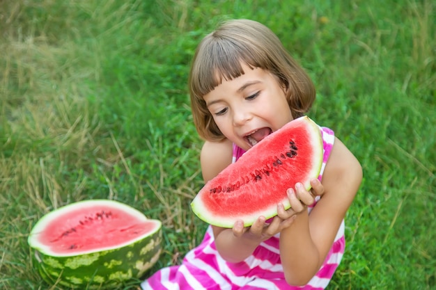 Il bambino mangia un'anguria nel giardino