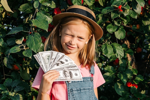 Il bambino mostra i dollari nelle sue mani Una ragazza con un cappello sorride e porge dollari