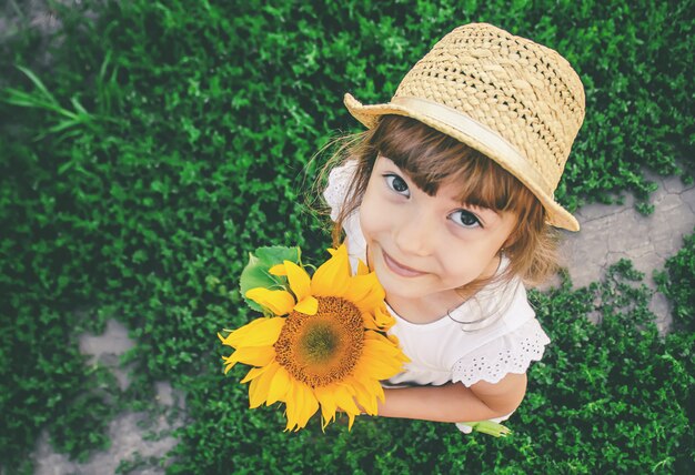 Il bambino nel campo dei girasoli è un piccolo contadino. messa a fuoco selettiva.